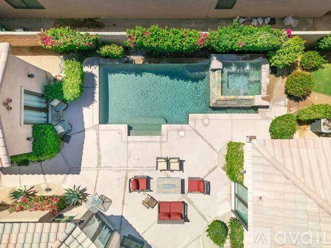 A pool surrounded by a patio with chairs and plants.