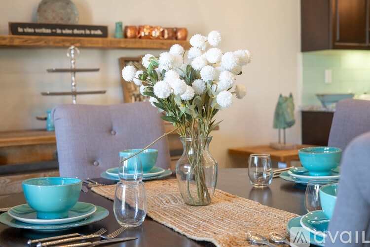 A dining table set with blue plates and a vase of white flowers.