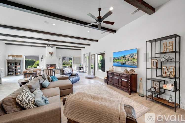 A spacious living room with a large couch and a painting on the wall.