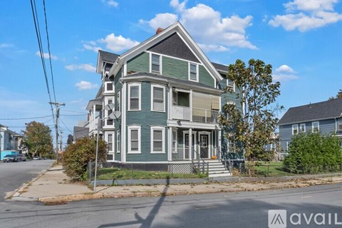 A two-story house with a green exterior and a white porch.