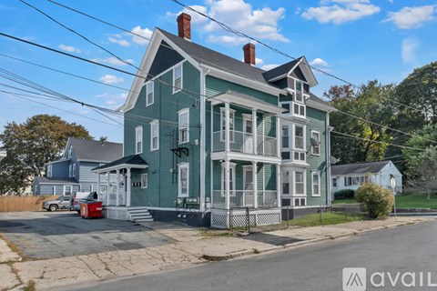 A green house with a red truck parked in front.