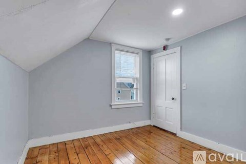 A room with wooden flooring and a window with blinds.