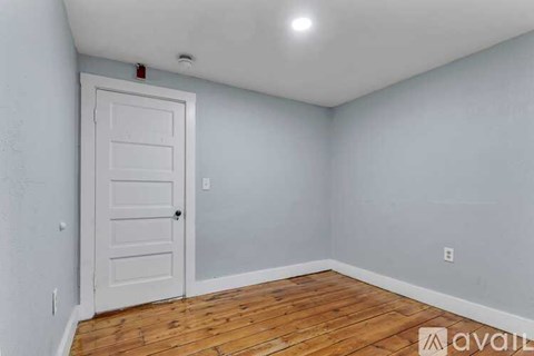 A room with a white door and wooden floor.