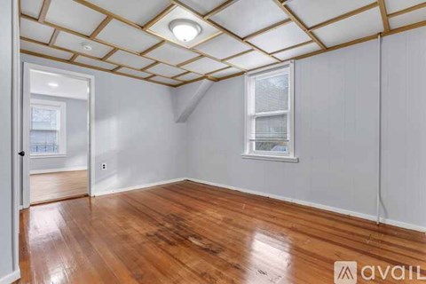 A room with wooden floors and a window with blinds.