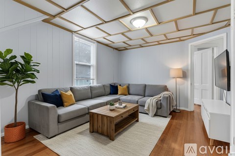 A living room with a grey couch, a wooden coffee table, and a plant in a pot.