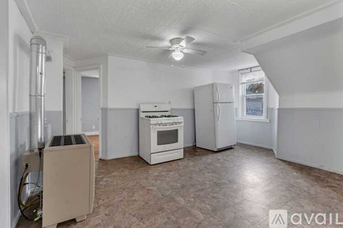 A kitchen with a stove, oven, and refrigerator in a room with a fan on the ceiling.
