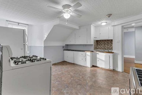 A kitchen with a white stove and a fan on the ceiling.