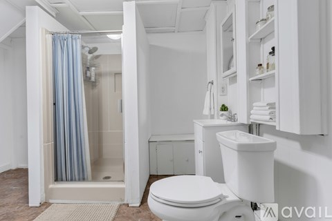 A white bathroom with a toilet, sink, and shower.