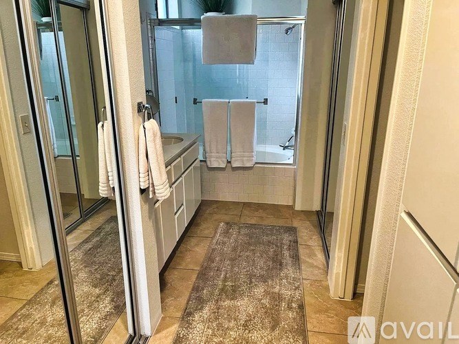 A bathroom with a glass shower door and a rug on the floor.