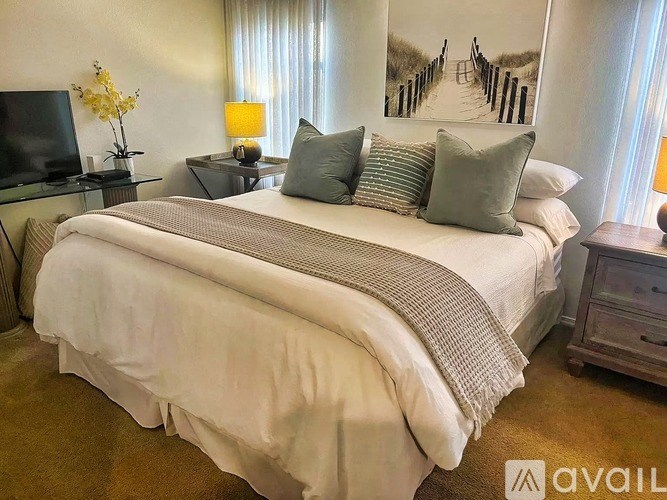 A bedroom with a large bed and a painting on the wall.