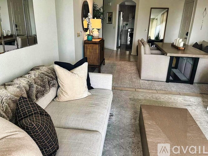 A living room with a couch, a coffee table, and a mirror.