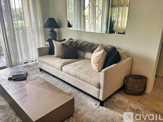A living room with a beige couch, a wooden coffee table, and a mirror on the wall.
