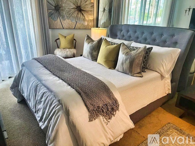 A bed with a grey headboard and multiple pillows is in the image.