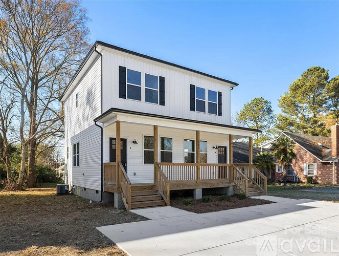 A two-story house with a white exterior and a wooden deck.