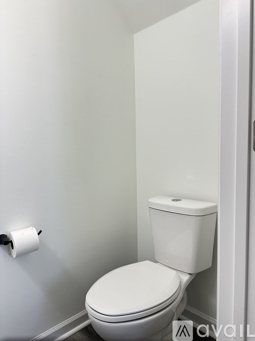 A white toilet with a toilet paper roll on the wall.
