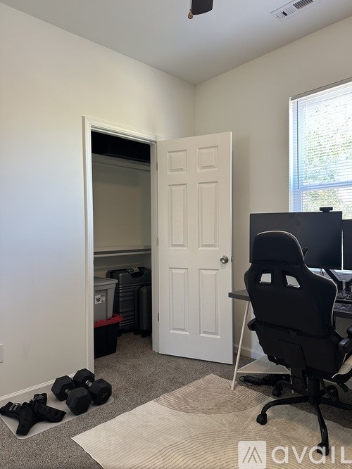 A room with a black chair, a white door, and a window.
