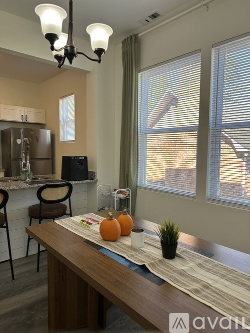 A kitchen with a table and chairs in front of a refrigerator.
