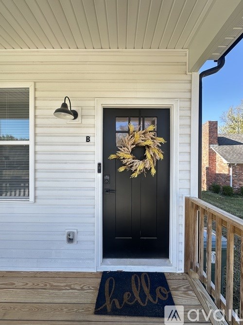A black door with a wreath and a mat that says hello.