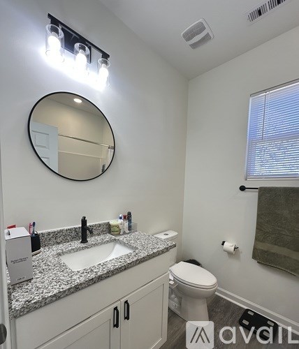 A bathroom with a granite countertop and a round mirror.