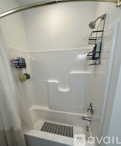 A white bathtub with a shower head and a shelf above it.