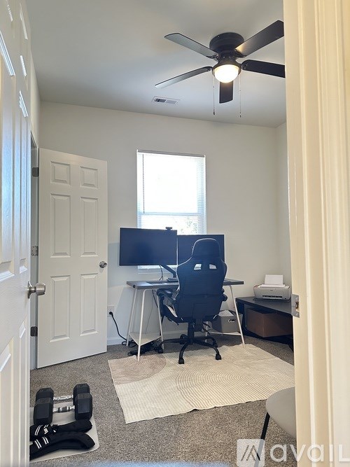 A room with a ceiling fan, a desk with a computer, and a chair.