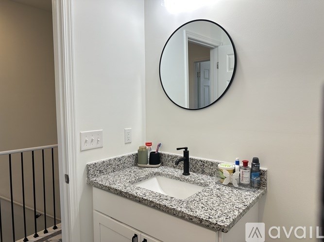A bathroom with a granite countertop and a round mirror.