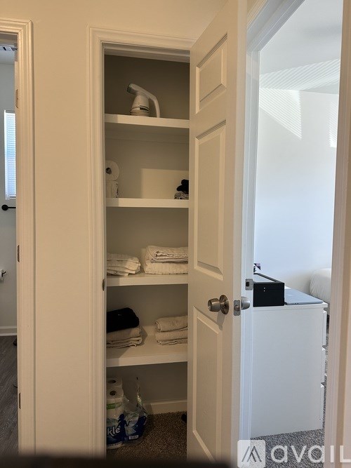 A white door is open to a small bathroom with a towel and a toiletries.