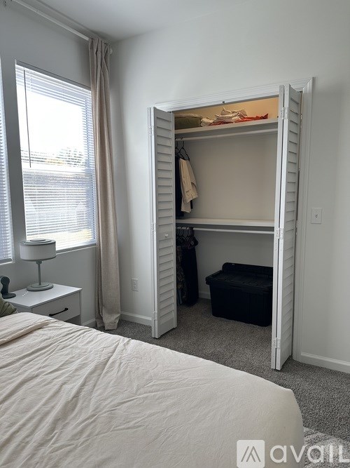 A bedroom with a white bed and a white dresser with a lamp on it.