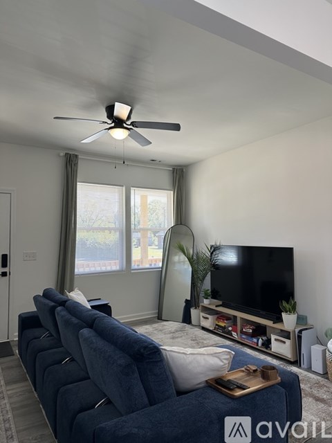 A living room with a blue couch and a television on a stand.