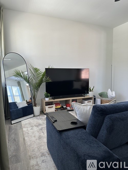A living room with a grey sofa and a TV on a stand.
