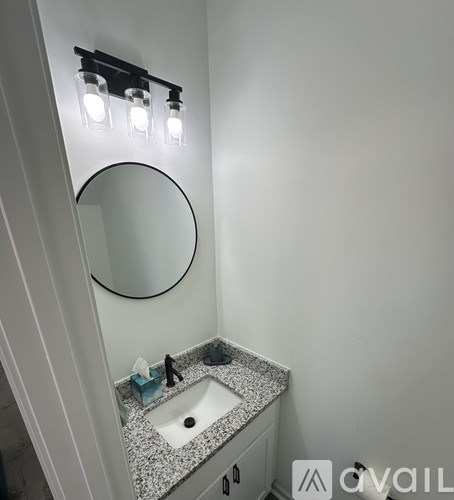 A bathroom with a sink, mirror and lights.