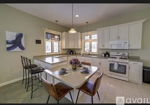 A kitchen with a table and chairs in the foreground and a painting on the wall.