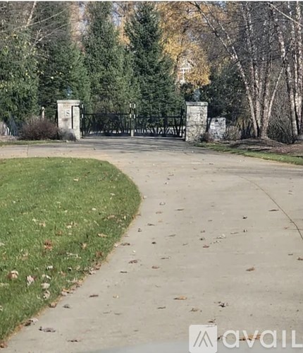 A pathway with a grassy area on the left and a metal gate on the right.