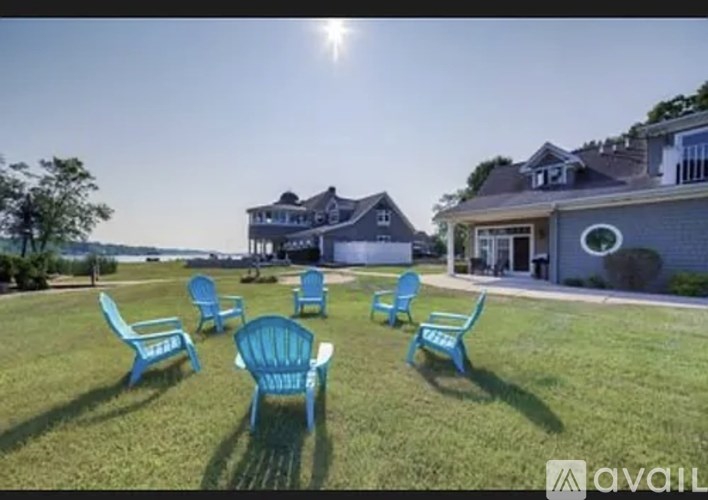 A lawn with blue chairs and a house in the background.