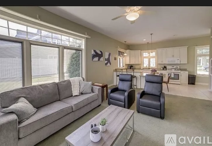 A living room with a grey couch, a coffee table, and two chairs.