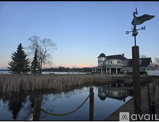 A house is reflected in the water in front of a dock.