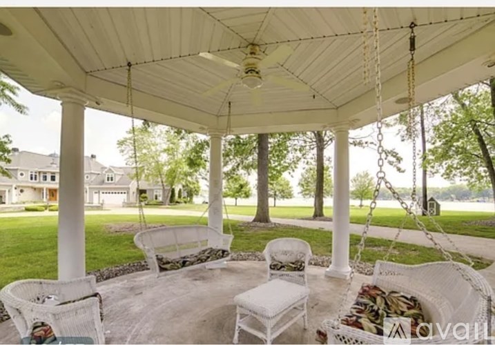 A white porch swing is suspended from a white gazebo.