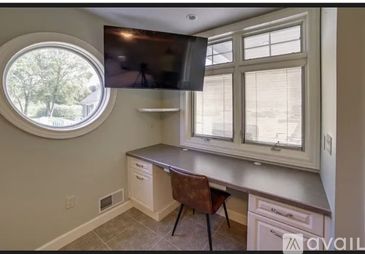A kitchen with a round window and a flat screen TV mounted above the counter.
