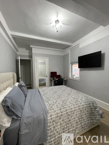 A bedroom with a bed covered in a grey and white patterned duvet.