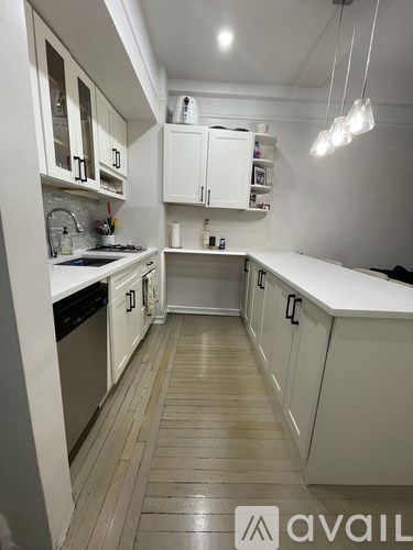 A kitchen with white cabinets and a wooden floor.