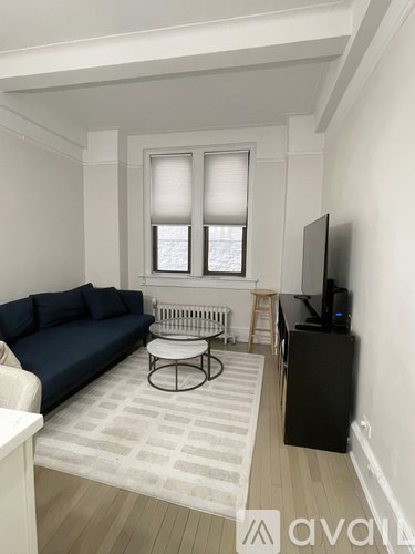 A living room with a blue couch, a white table, and a television.