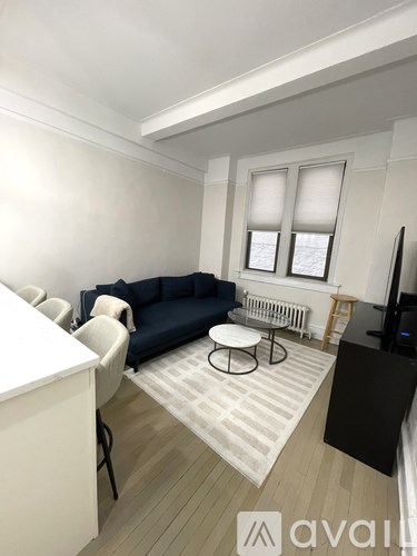 A living room with a black couch, white table, and a striped rug.