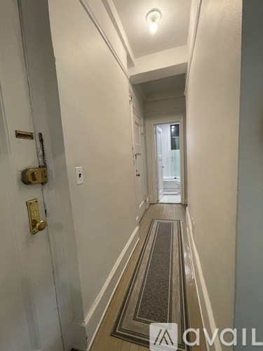 A hallway with a carpeted floor and a door on the left.