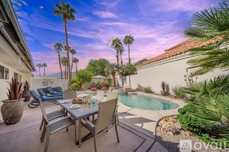 A patio with a table and chairs overlooks a pool.
