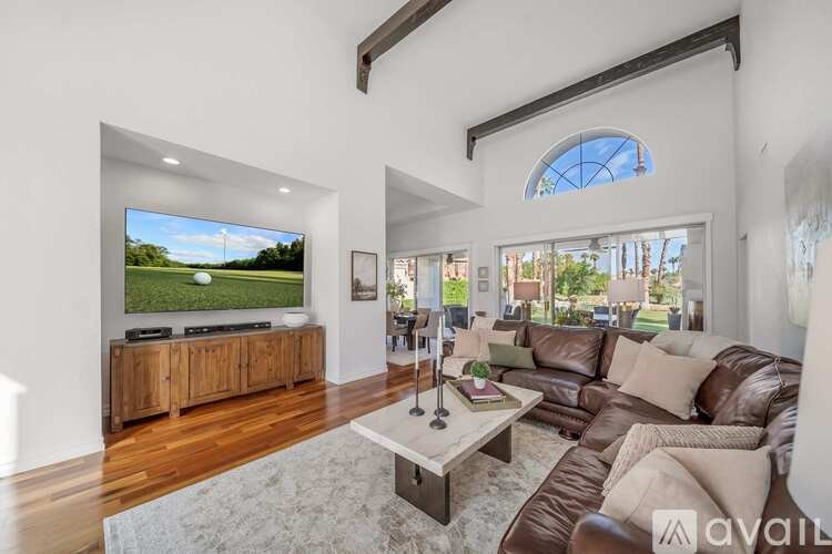 A modern living room with a large TV and brown leather sofa.