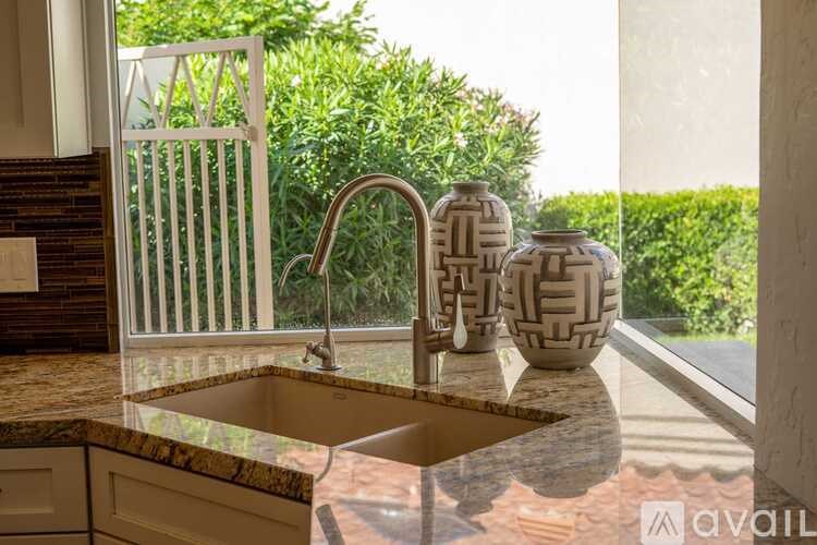 A kitchen sink with a faucet and two vases on the counter.