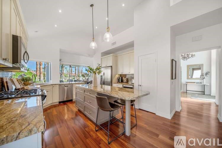 A kitchen with a marble countertop and a dining table with chairs.