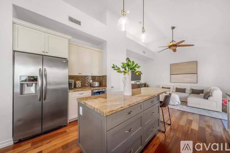 A modern kitchen with a refrigerator, stove, and island with a plant on it.