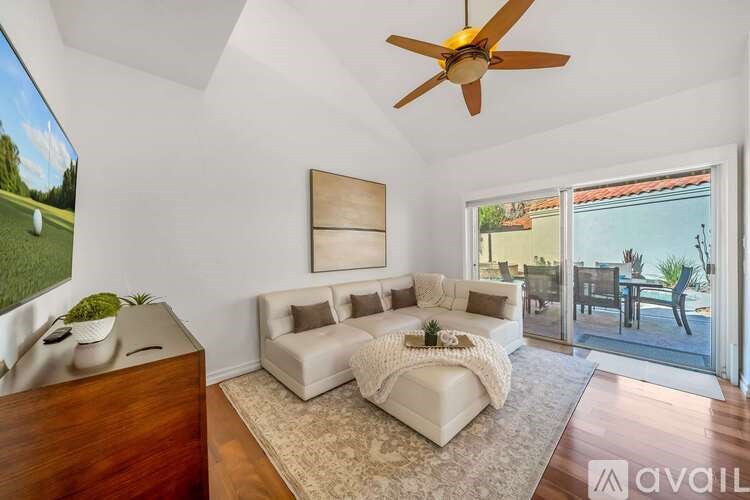A living room with a white couch and a ceiling fan.