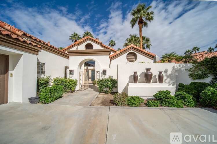 A house with a driveway and a palm tree in front.